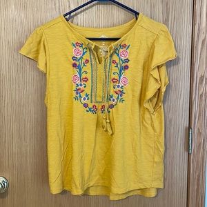 Mustard colored top with embroidered flowers and tassel